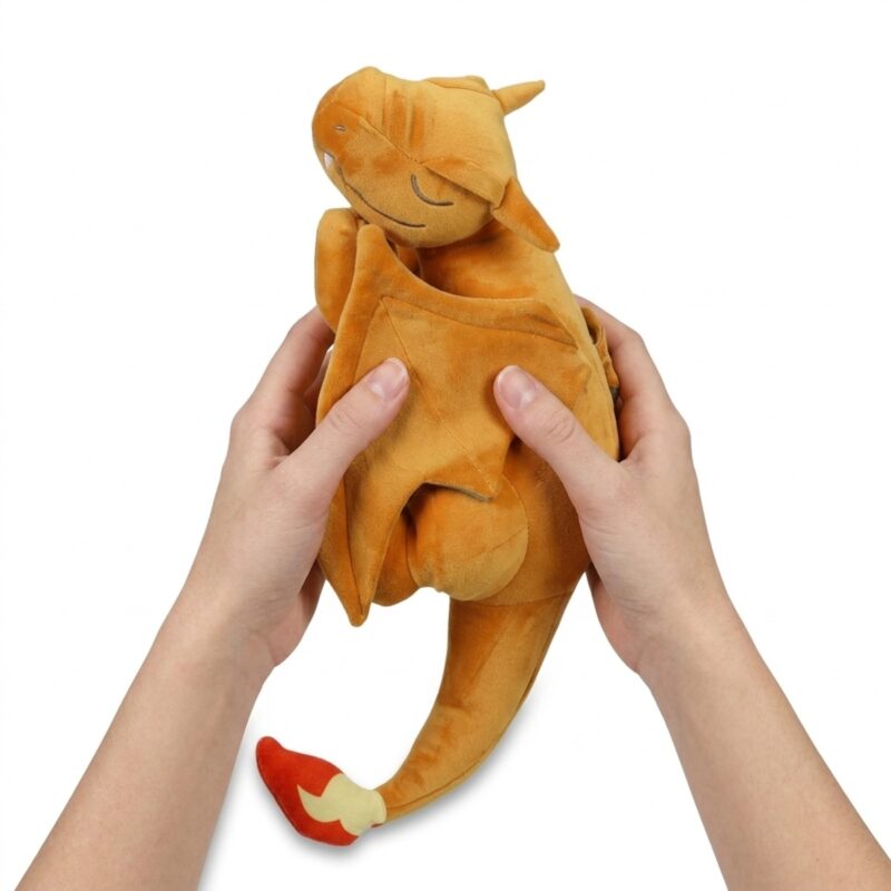 Peluche Charizard durmiendo sostenido en las manos
