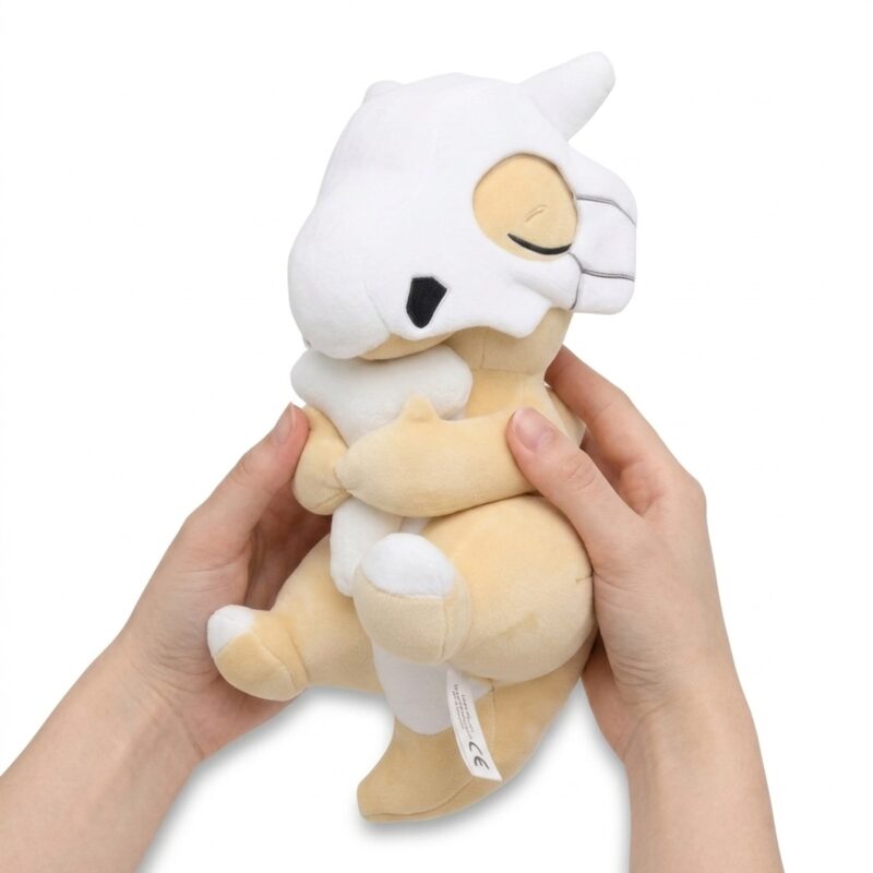 Peluche Cubone durmiendo sostenido en las manos
